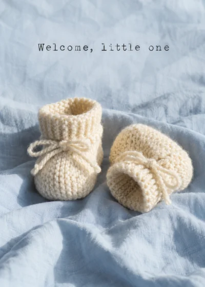 Knitted baby booties on blue cotton. Welcome, little one.